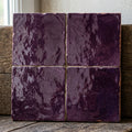 Four purple square tiles with glossy textured surfaces and irregular edges