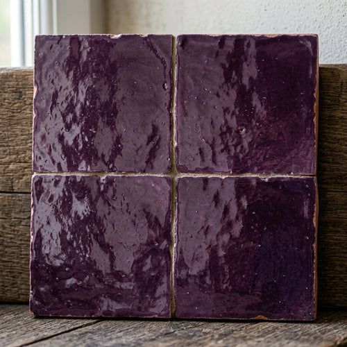 Four purple square tiles with glossy textured surfaces and irregular edges