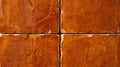 Four orange square tiles with textured surfaces and irregular edges