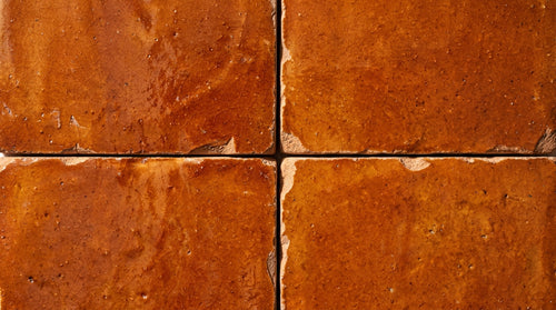 Four orange square tiles with textured surfaces and irregular edges