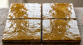 Four yellow square tiles with glossy textured surfaces and irregular clay edges